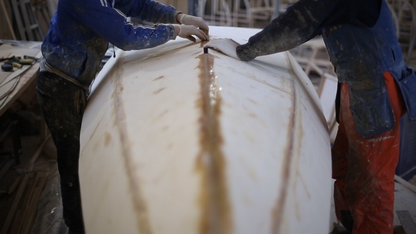 The carpenter Seals the Joints of the Boat at the Shipyard alt