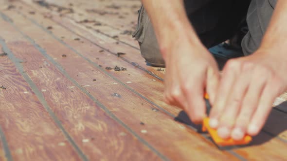 Using scraping tool ring excess mastic sealant on pine planking boat roof restoration. REAL TIME. alt