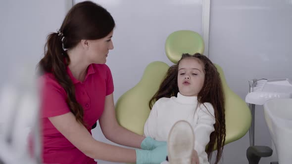 The Female Dentist Preparing a Child Patient Playfully for Dental Treatment alt