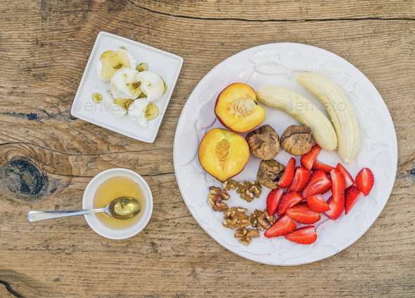 Breakfast set with fresh strawberry, banana, peach, dry figs, wa