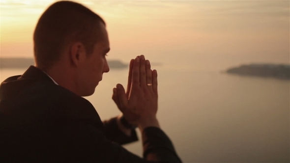 Handsome Groom  Prays At Sunset Sky Background