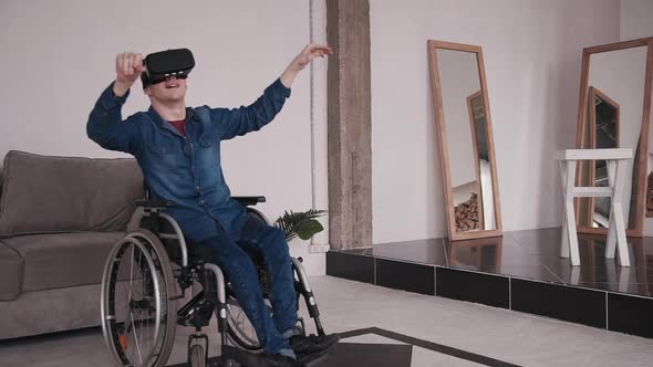 Young Man in Wheelchair in Virtual Reality Helmet Watching Video