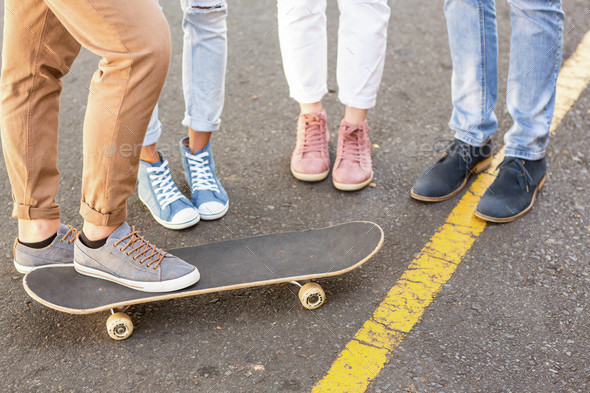 Lower section of hip friends and skateboard on the street
