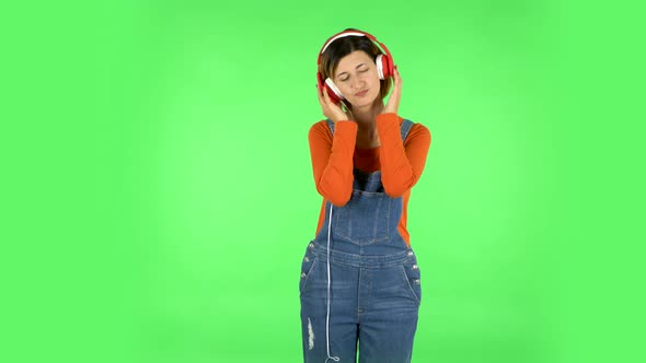 Cheerful Girl Dancing and Enjoys Music in Big Red Headphones. Green Screen alt