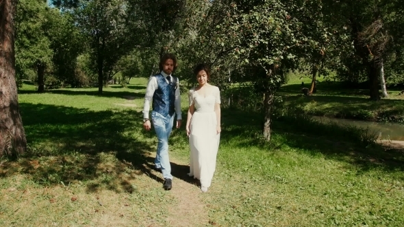 Young Beautiful Couple Walking In The Park , Holding Hands alt