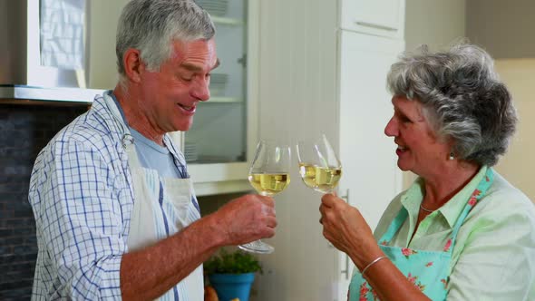 Senior couple interacting while having wine in kitchen 4k alt
