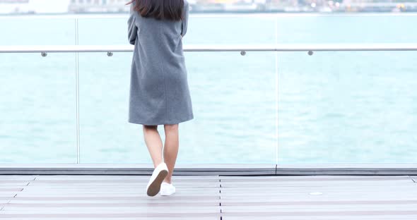Woman walking to harbour front and talk to cellphone  alt