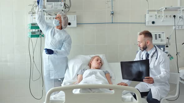Male Doctor Talking to Female Patient in Hospital Bed alt