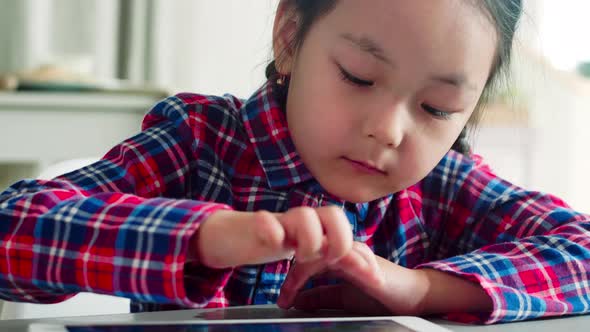 Cute Preschool Asian Girl Playing on Digital Tablet