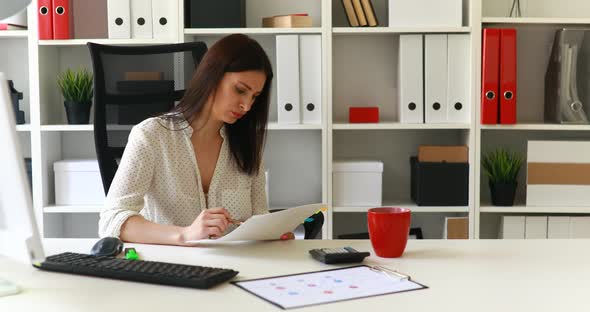 Businesswoman Sitting in Office Chair and Looking in Documents