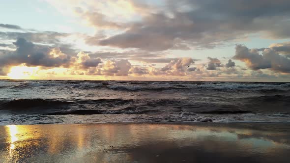 Coast of the Baltic Sea during a storm. Sunset, soft golden sunlight, glowing clouds.