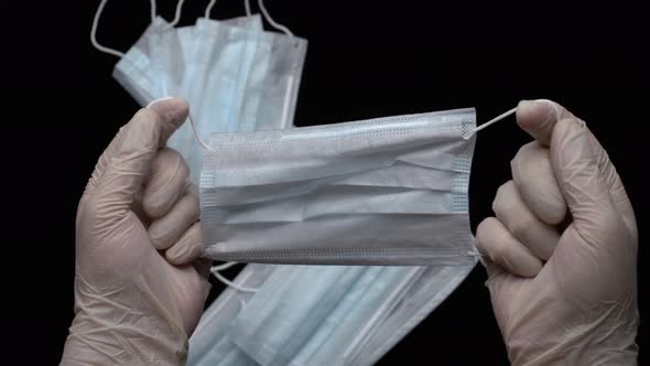 Doctor Showing Respiratory Face Mask Holds in Hands Medical Gloves on Black Background