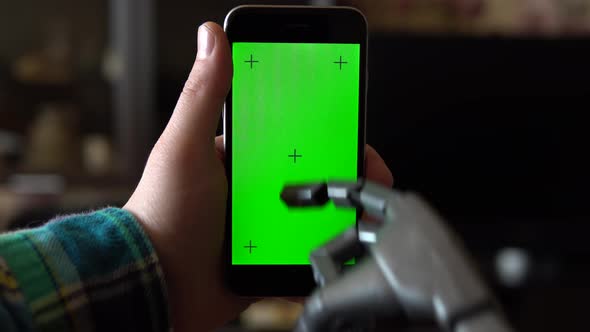 Cyborg Uses the Phone. Gray Mechanical Hand Swipe Up on Smartphone with Green Screen. Chroma Key. alt