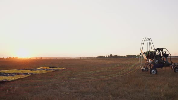 Motor Paraglider Ready To Fly in the Sky Against the Setting Sun in Warm Sunlight. alt