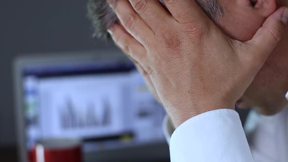 Businessman Holding His Head on the Background of the Computer