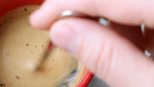 Red cup of hot coffee. Man stirring in a cup of espresso. alt