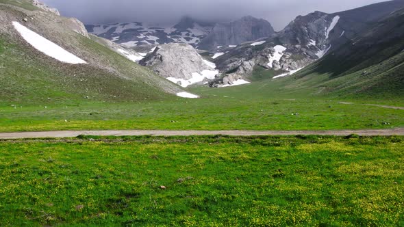 Green plateau among snowy mountains