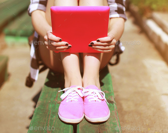 Cool girl with digital tablet pc resting in the city park