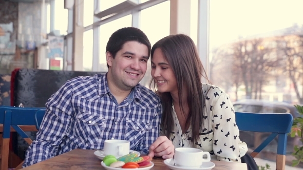 Happy Loving Couple In Cafe Laughing, Drinking Tea. Using Tablet For Fun. First Date.  alt