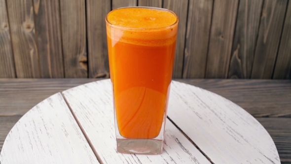 Carrot Juice Into Glass  Rotating, Wood Background alt