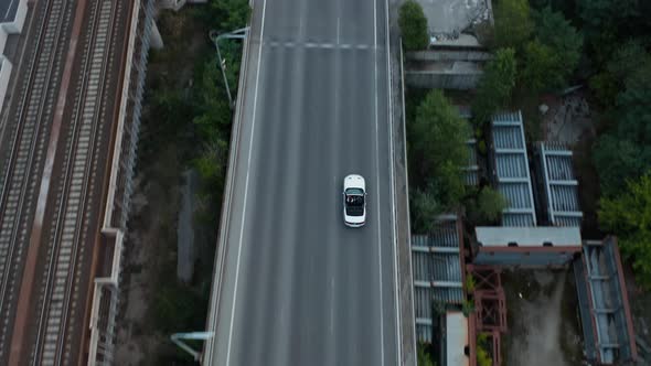 Aerial drone shot of a car driving on a bridge. alt