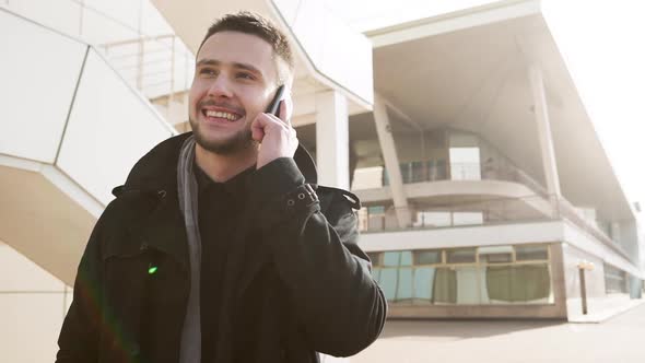 Handsome Young Caucasian Male Talking on Mobile Phone Standing Outdoors alt