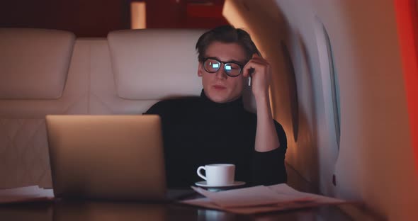 Handsome Businessman Putting on Earphones and Relaxing Flying First Class alt