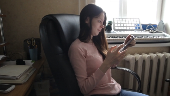Woman Working On a Tablet While Sitting In a Chair