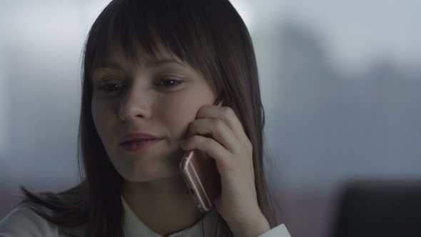 Young Woman Laughing On The Phone Sitting At Her Desk alt