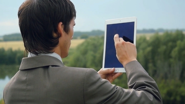 Young Businessman Standing On Edge Of Rock Mountain And Using Tablet Pc