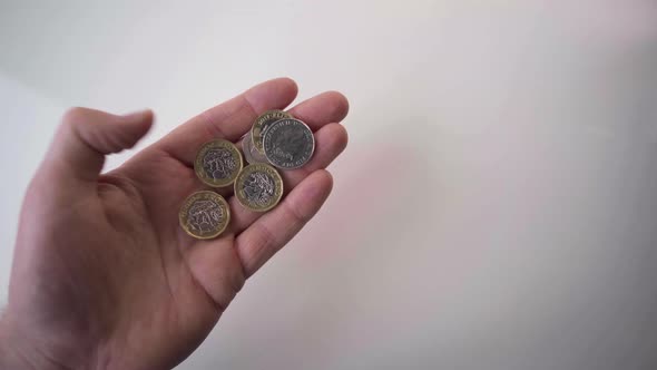Obverse And Reverse Five Pieces British One Pound Coins In Hand On White Background - High-Angle Sho alt