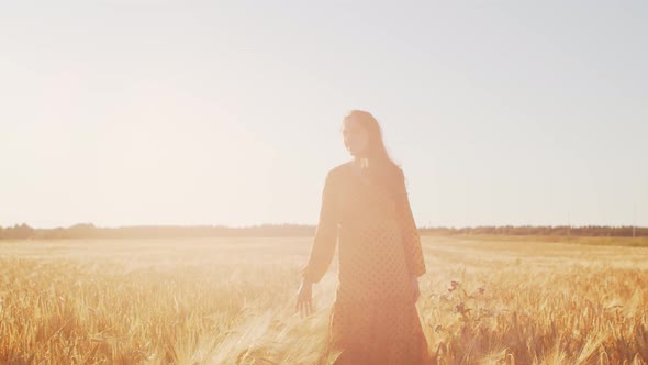 Pregnant woman in the rays of the sunset in the field alt