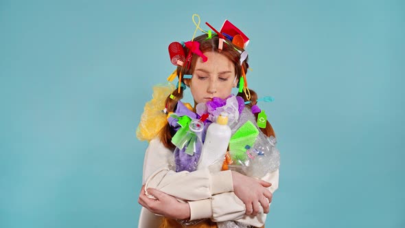 Unhappy girl holding plastic garbage. 