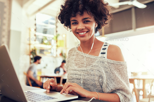 Happy young african woman at cafe with a laptop
