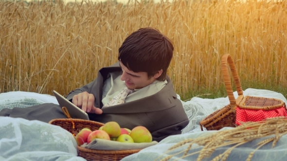 Young Handsome Businessman Use Tablet On a Picnic In Wheat Field