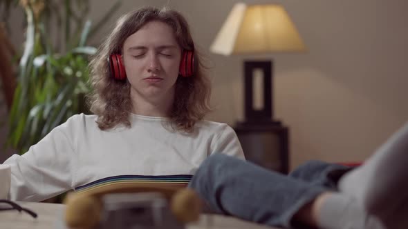 Portrait of Happy Relaxed Young Man in Headphones with Closed Eyes Listening to Music Imitating alt