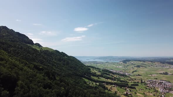 Drone flight on the boarder from a big forest on a mountain next to some villages in a valley in the alt