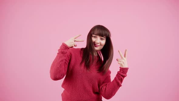 Young Caucasian Woman with Windblown Brown Hair Wearing Red Knitted Sweater While Showing Vsign with alt