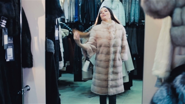 Beautiful Brown-haired Girl Chooses a Fur Coat In The Store