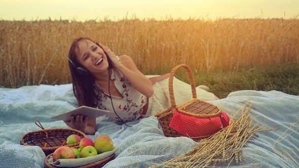 Young Pretty Woman On Picnic Listening To Music In Wheat Field