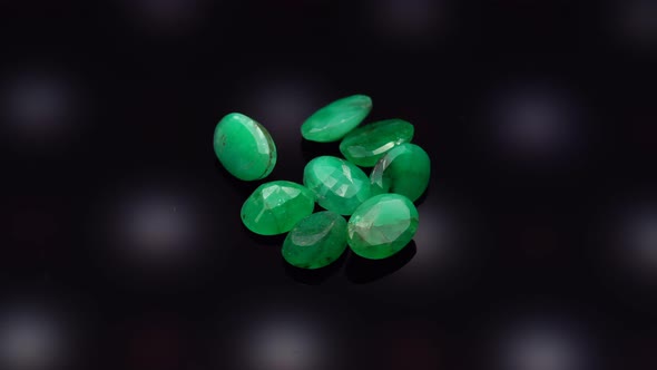 Natural Green Emerald on the Turning Table on the Black Background