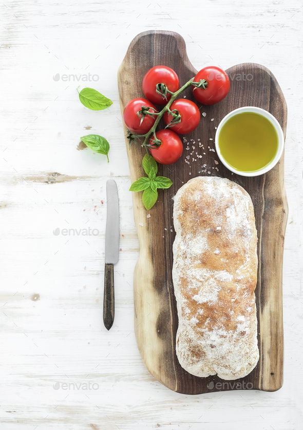 Freshly baked ciabatta bread with cherrytomatoes, olive oil, basil and salt Stock Photo by