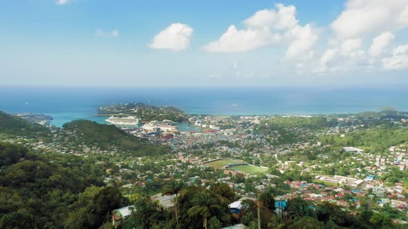 Drone camera taking the town in a dense forest from a cliff (Rodney Bay, Saint Lucia) alt
