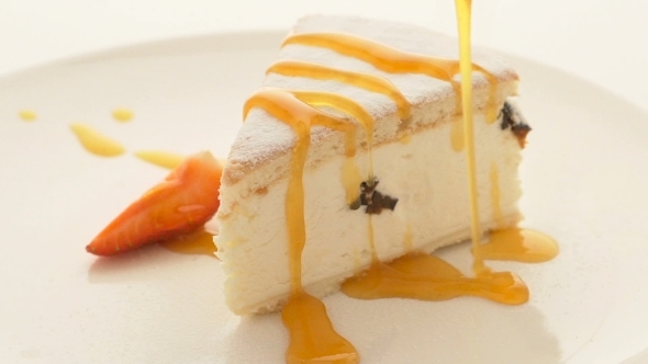 Slice Of Cheesecake With Pouring Sauce On Plate On White Table