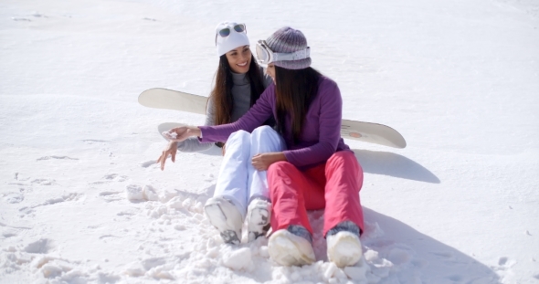 Two Young Women Sitting Chatting In The Snow alt