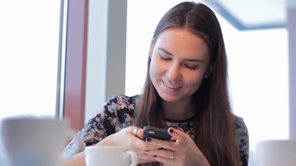 Smartphone Girl Using App On Phone Drinking Coffee Smiling In Cafe. 