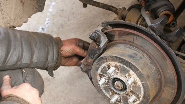 Auto Mechanic Working On Brakes In Car Repair Shop alt