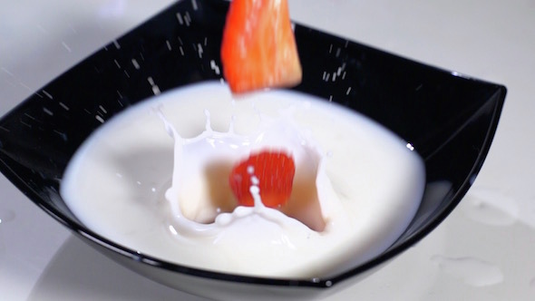 Sliced Strawberries Falling In Milk