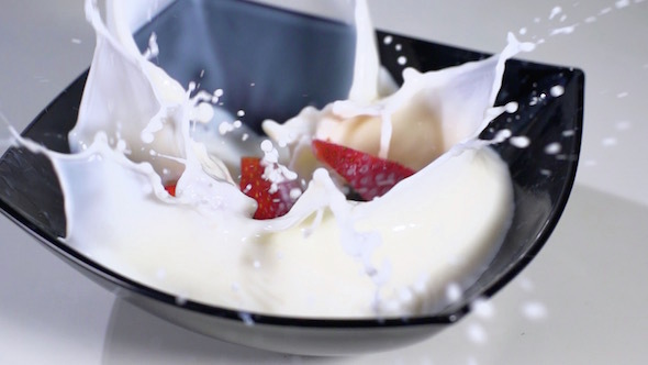 Sliced Strawberries Falling In Milk