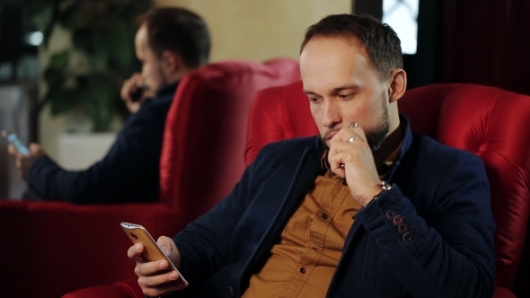 Man Looking To The Phone And Smoking Electronic Cigarette alt
